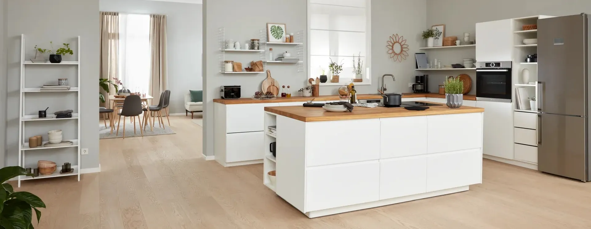 Heldere, moderne keuken met witte kasten, houten aanrechtbladen, en open rekken weergeven decor.