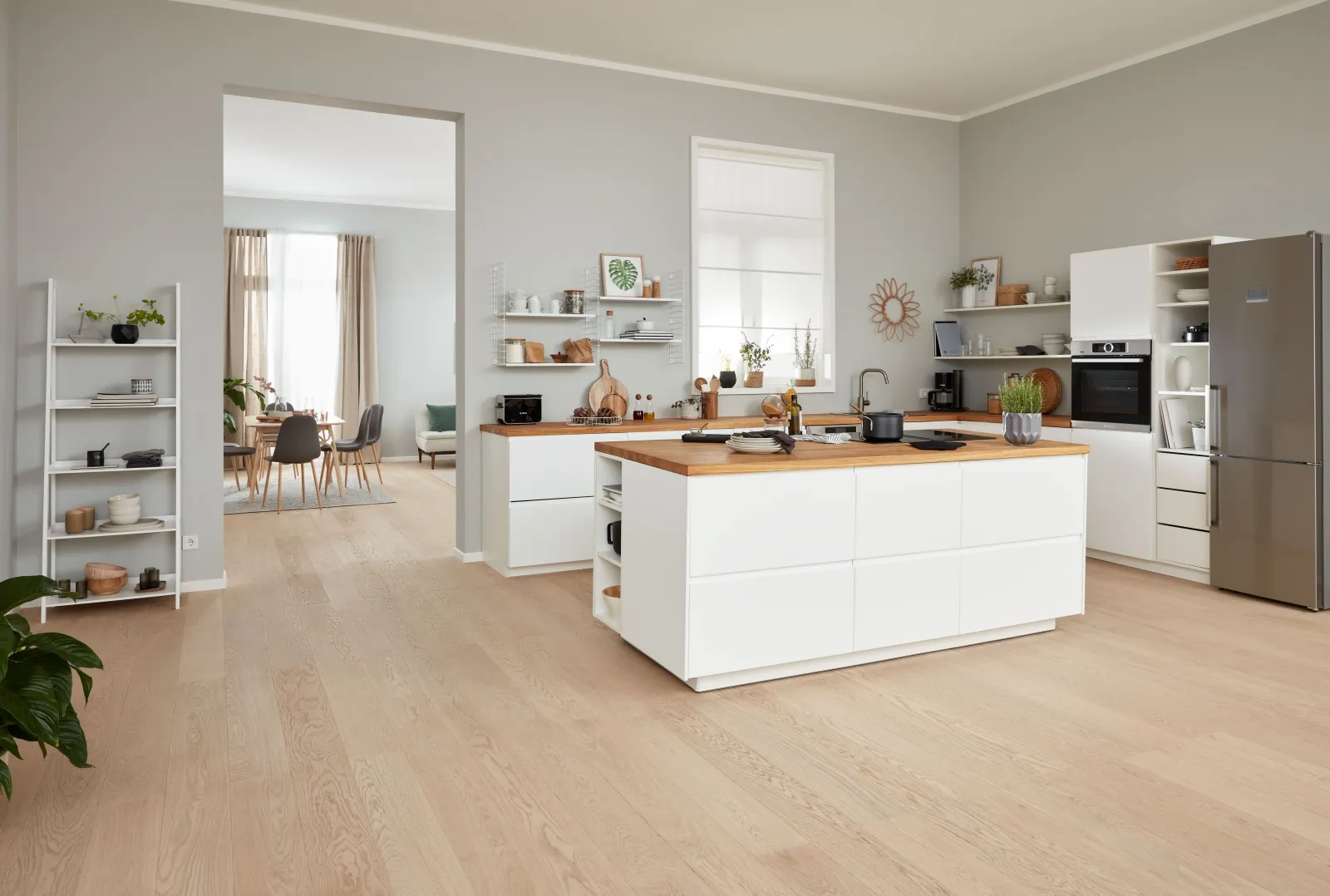 Ruime moderne keuken met witte kasten, houten aanrechtbladen en open rekken.