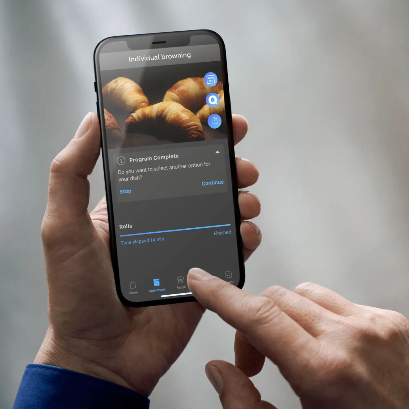 Smartphone displaying image of croissants, hand holding device, mobile app interface.