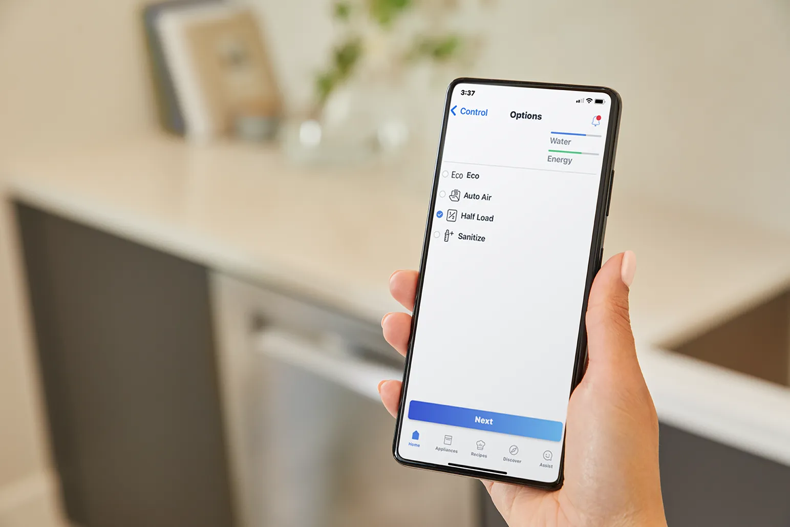 Hand holding smartphone with app controlling dishwasher settings like Eco and Half Load.