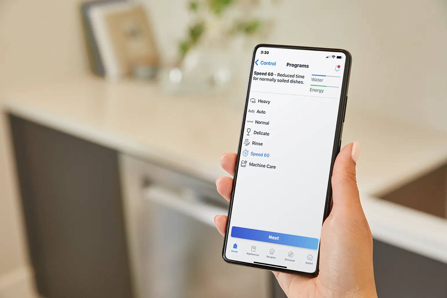 Hand holding smartphone showing a dishwasher app with various cleaning programs.