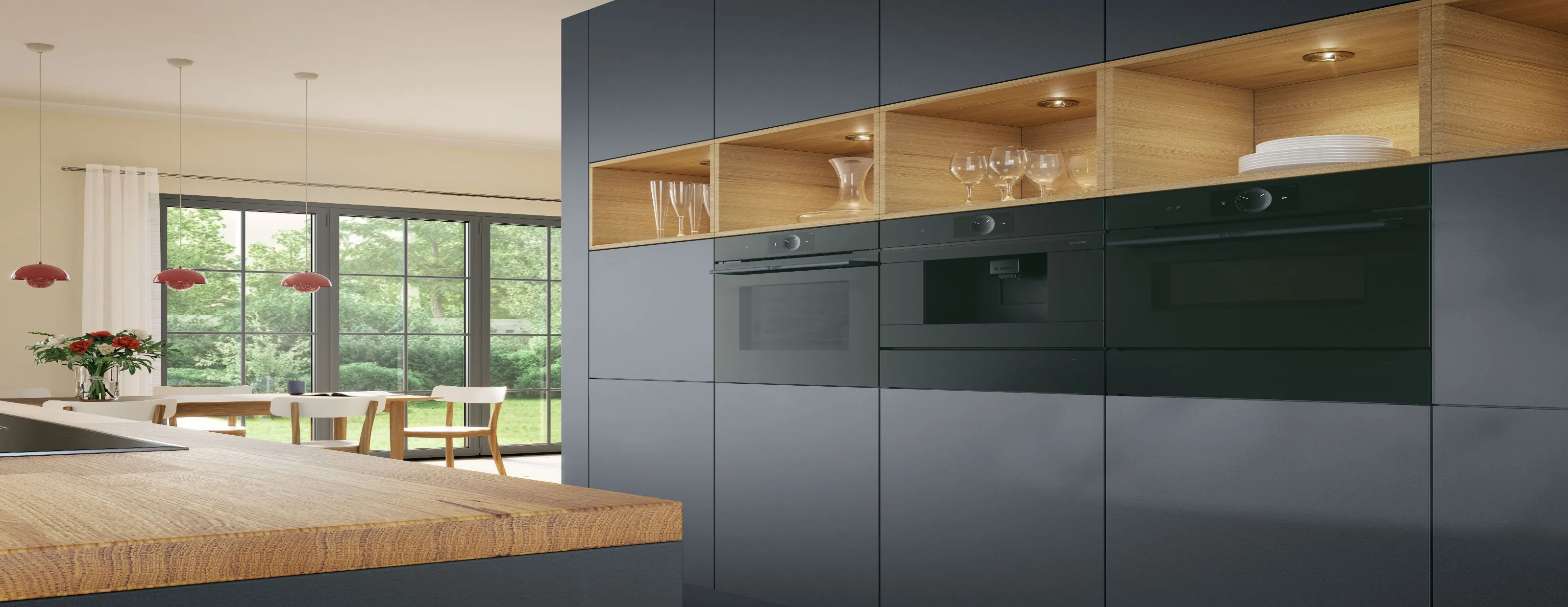 Modern kitchen wall of dark cabinets with two built-in ovens and illuminated open wood shelves, adjacent to a dining area with large windows.