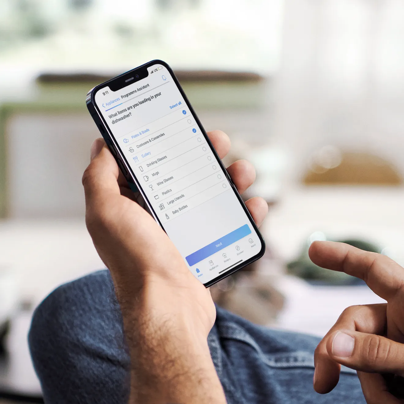 Detalle de un usuario programando su lavavajillas mediante la app Home Connect en su teléfono móvil con la ayuda del programa inteligente