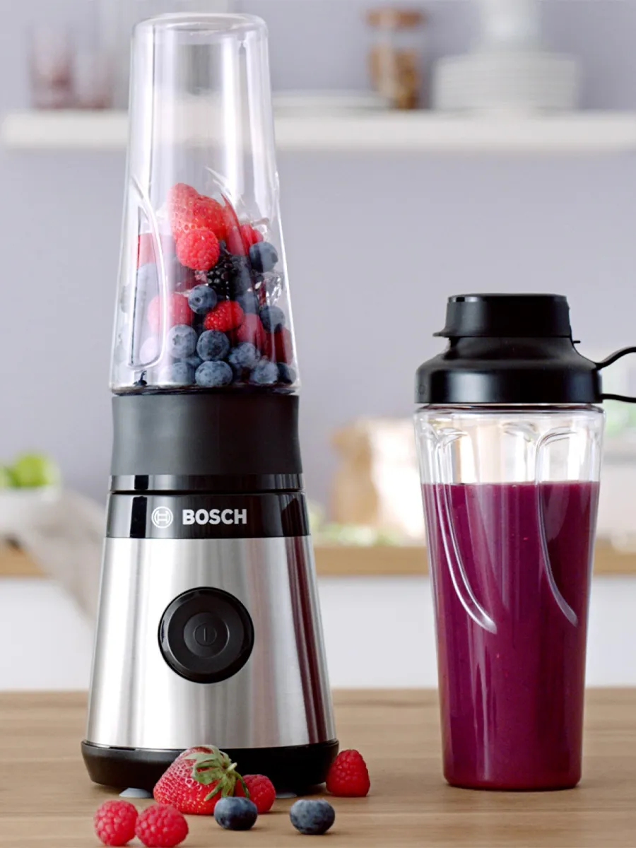 Miniblender VitaPower Series 2 with red fruits and a smoothie-filled To-Go-Bottle on a kitchen shelf.