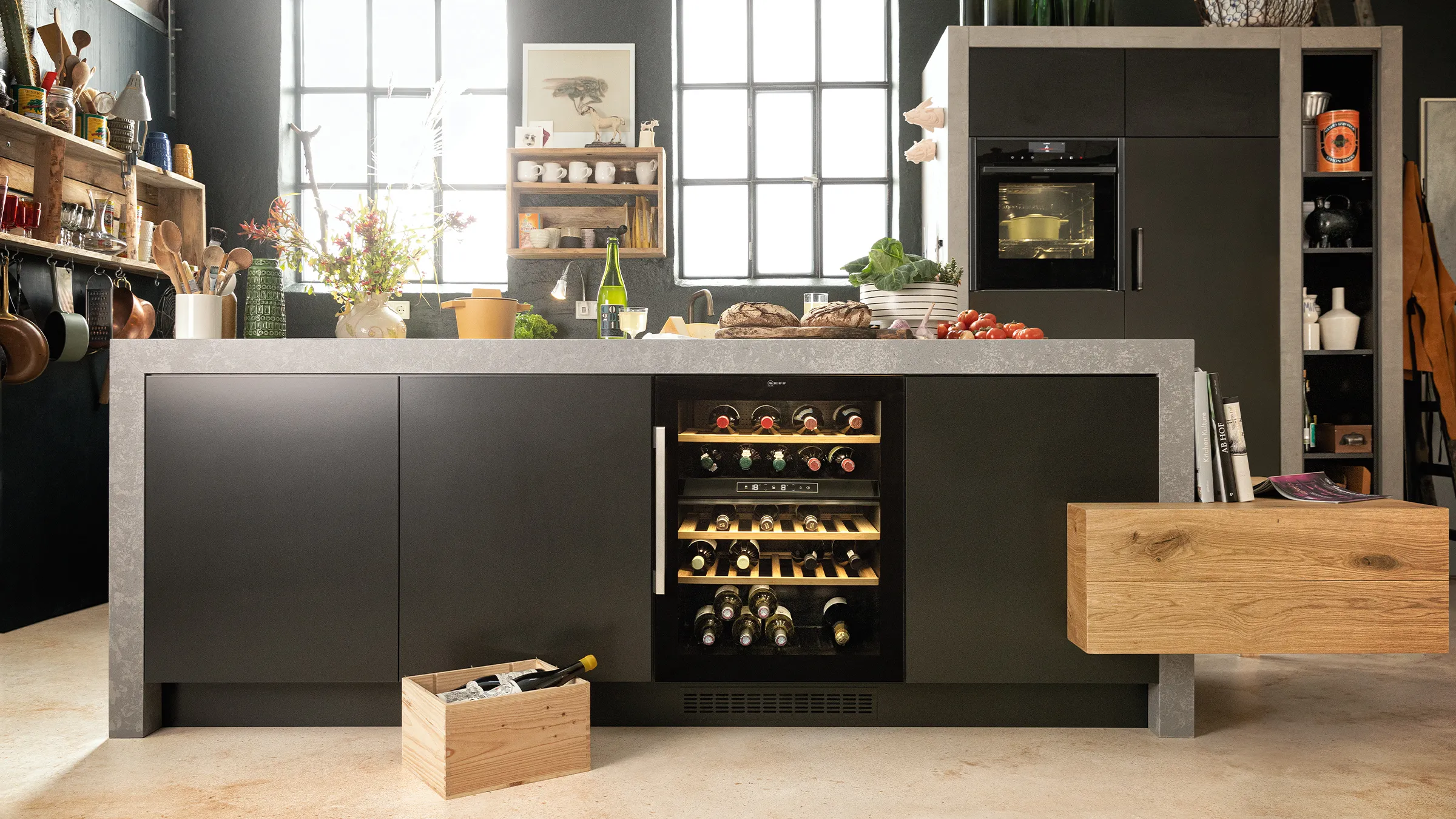 Modern kitchen with sleek black cabinets, wine cooler, shelves, and various cooking utensils and ingredients.