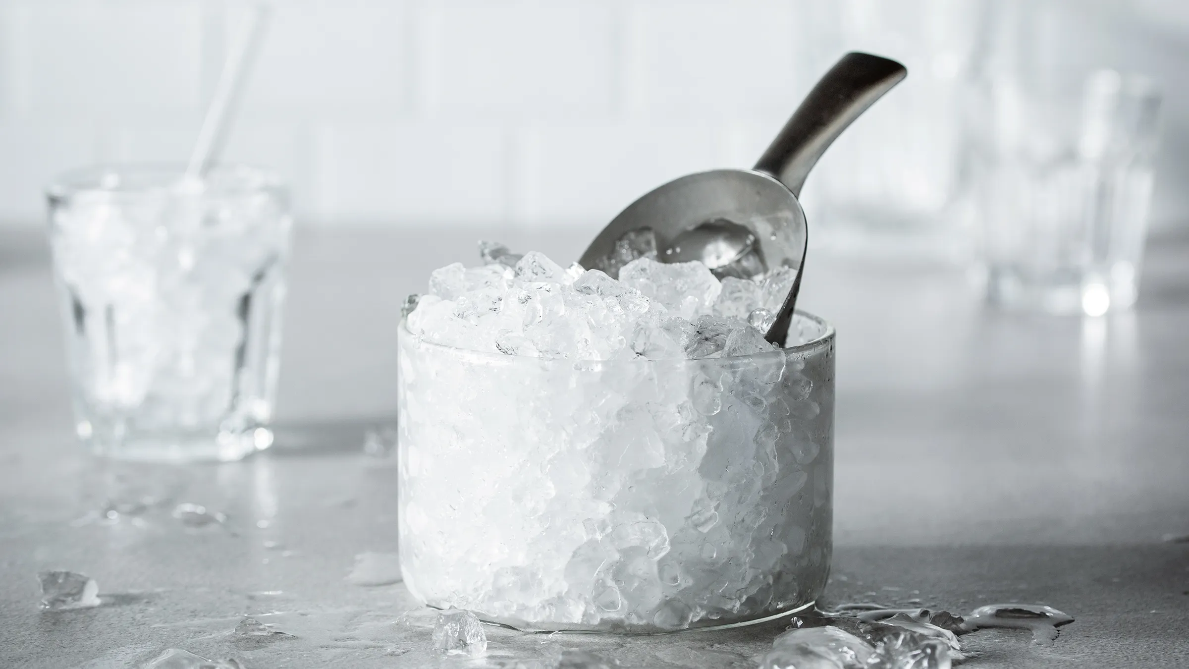 Buzla dolu şüşə butulkanın yanında əzilmiş buzla dolu spatulalı şüşə konteyner.