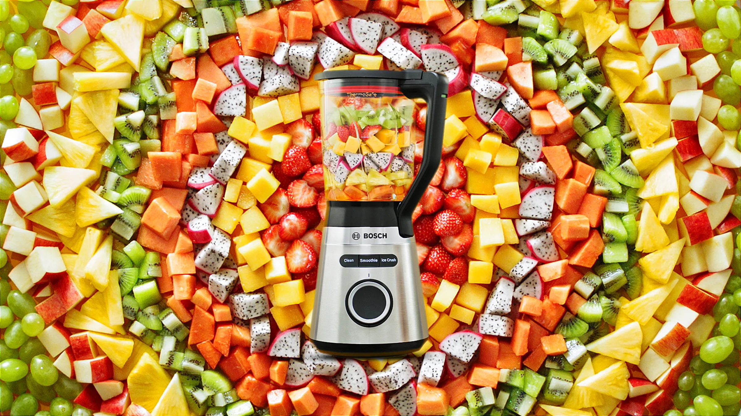 Cihazların ətrafında çox rəngli dairələr əmələ gətirən doğranmış meyvə və tərəvəz ilə VitaPower Series 4 blender.