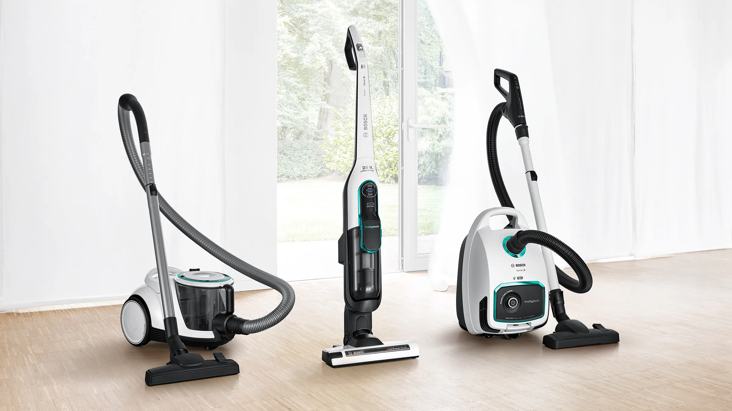 A range of ProHygienic vaccums stand in a room where a breeze from an open sliding door blows a curtain the background.