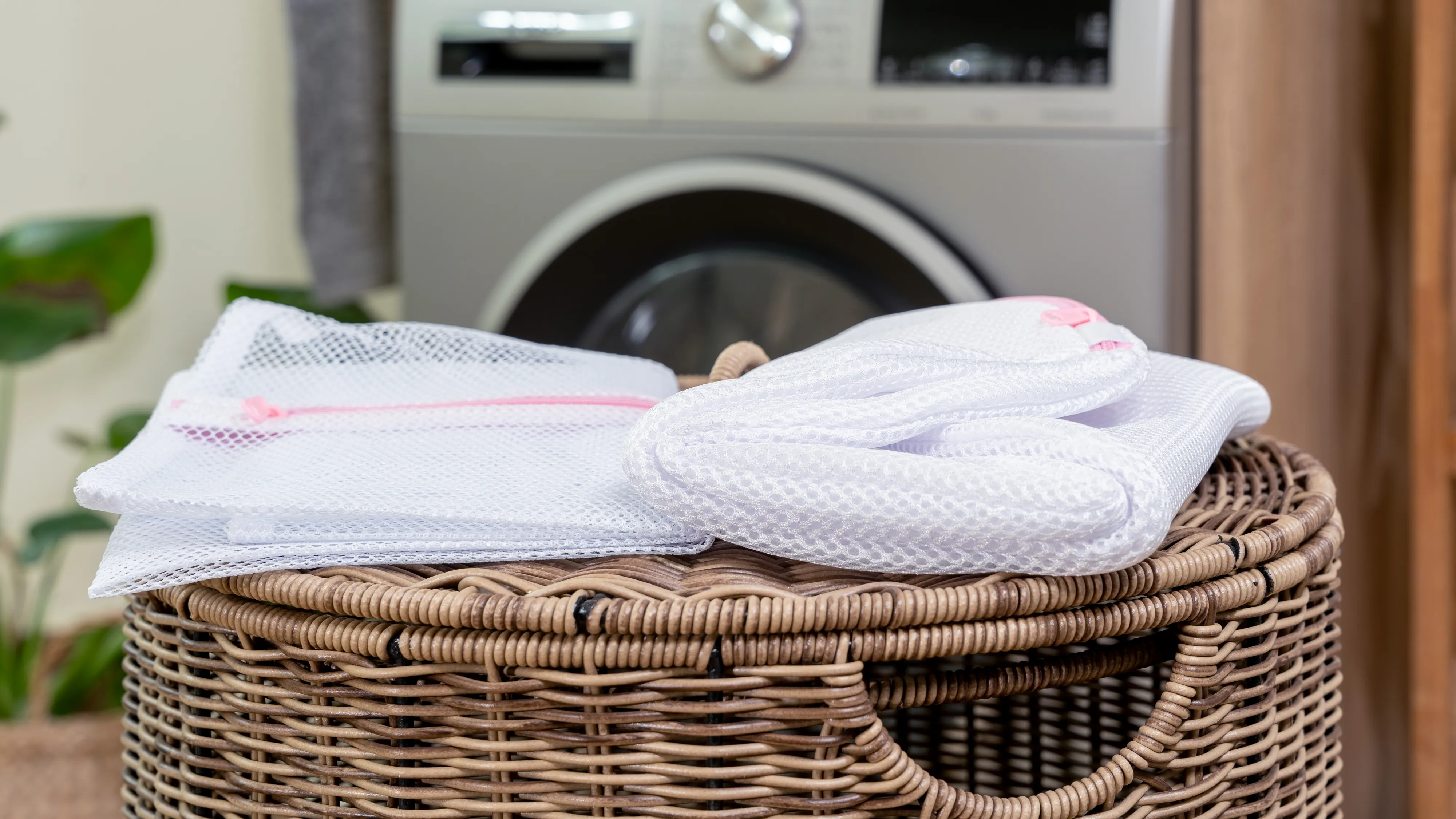 Panier de blanchisserie avec des vêtements pliés, machine à laver en arrière-plan, environnement propre et organisé maison.