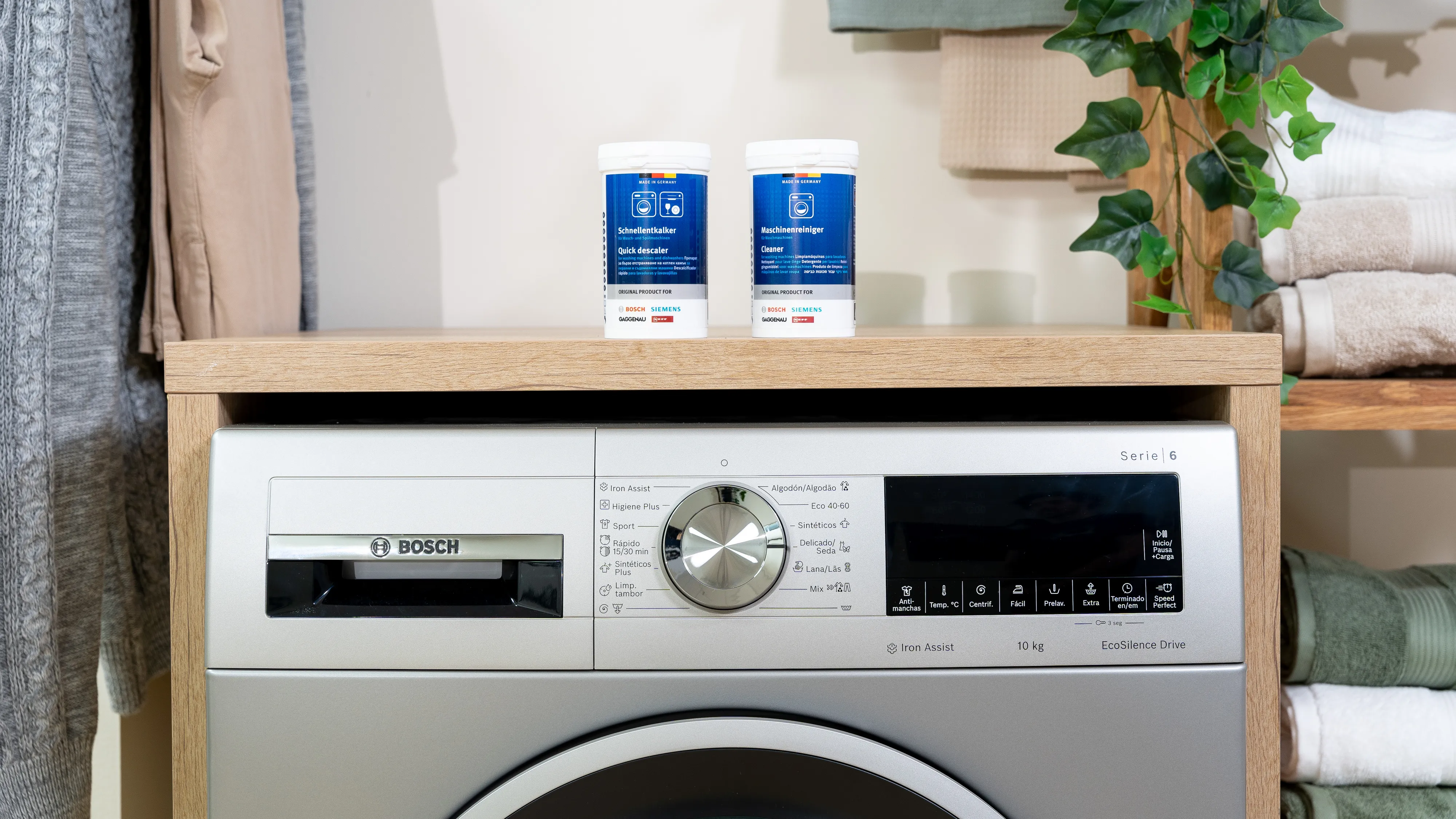 Machine à laver avec détergent, plante et serviettes dans un cadre familial.