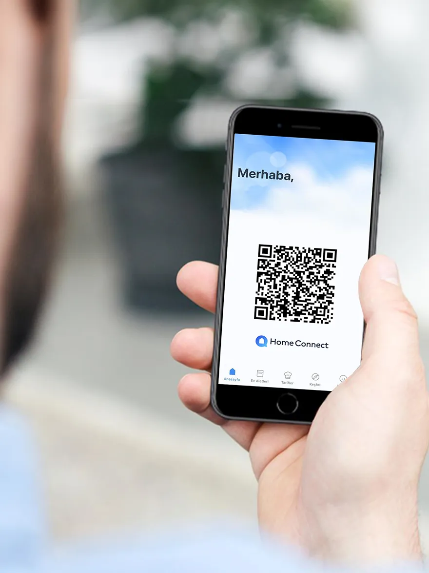 Akıllı telefonlar "Merhaba" ve HomeConnect uygulaması için QR kodu, bulanık arka plana karşı el tuttu.