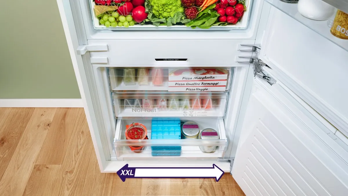 koel-vriescombinatie met deur open en goedgevulde lades met etenswaren