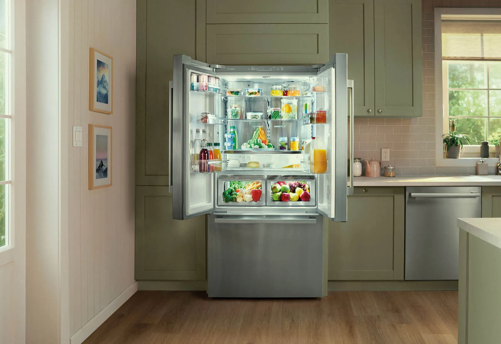 Couple standing in kitchen near open fridge, holding and showing various fresh vegetables.