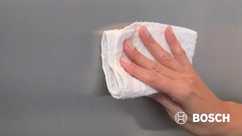 Hand wiping a surface with a white cloth, Bosch logo visible in the corner.