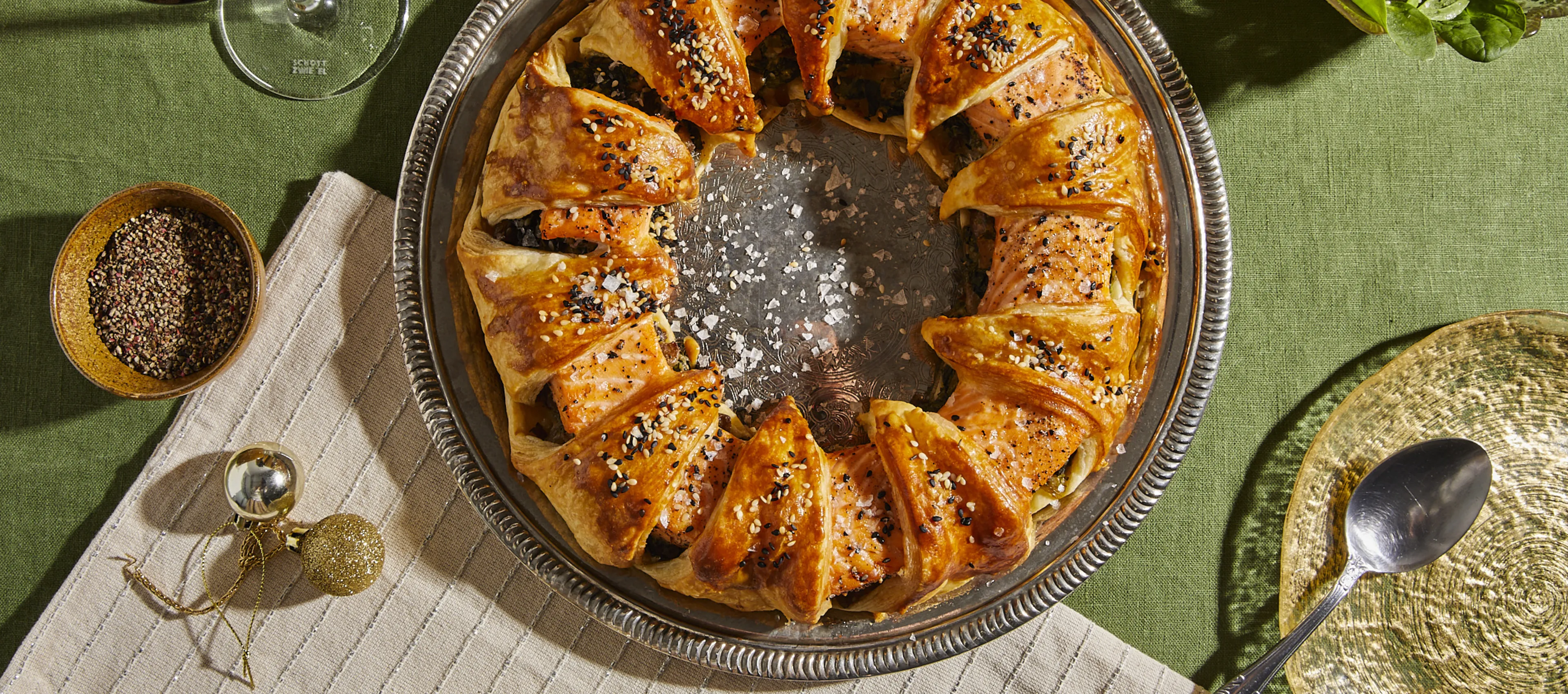 Circular pastry dish with caramelized topping, surrounded by spices, herbs, and a wine glass.