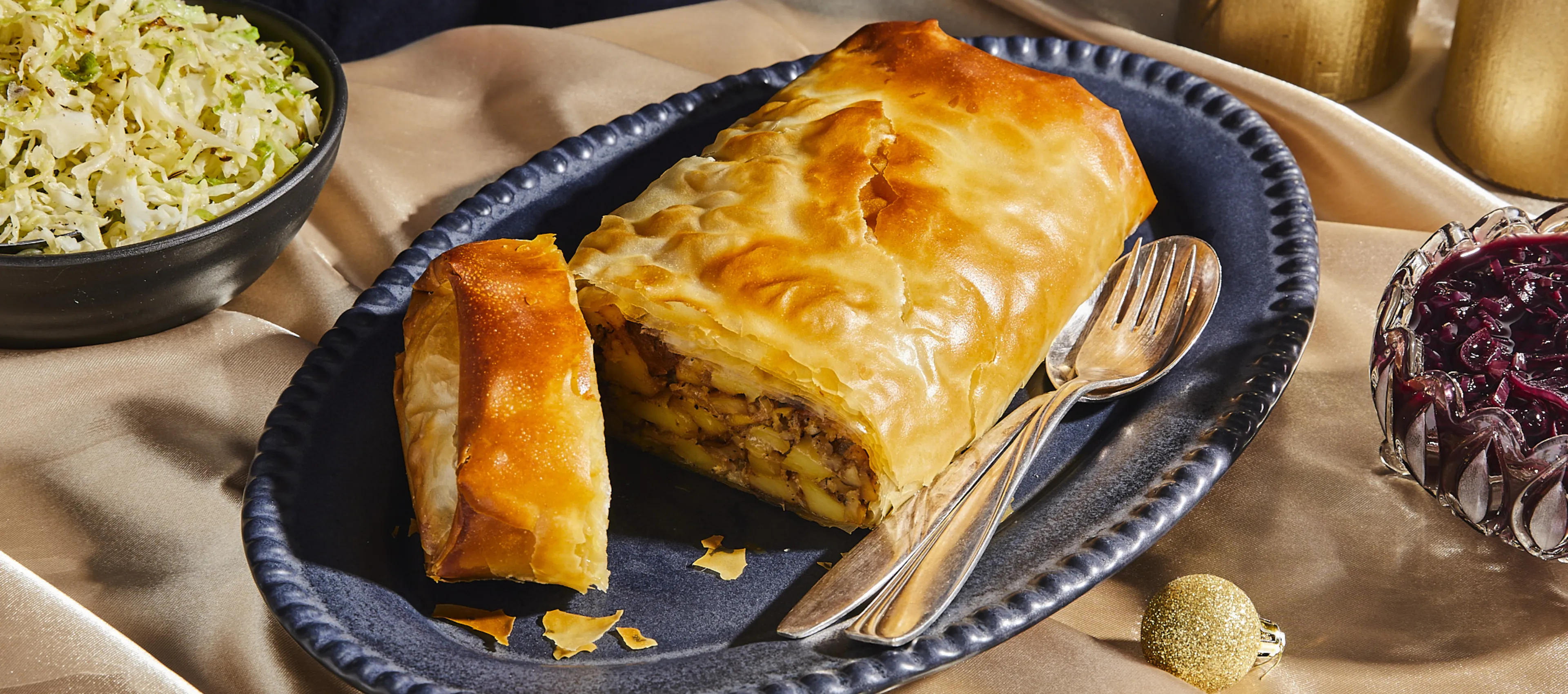 Savory meat pie with flaky crust, served with side of coleslaw and cranberry sauce on a rustic table setting.