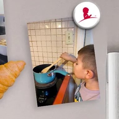 Child stirs food in a blue pot on a stovetop, with a croissant and icon nearby.