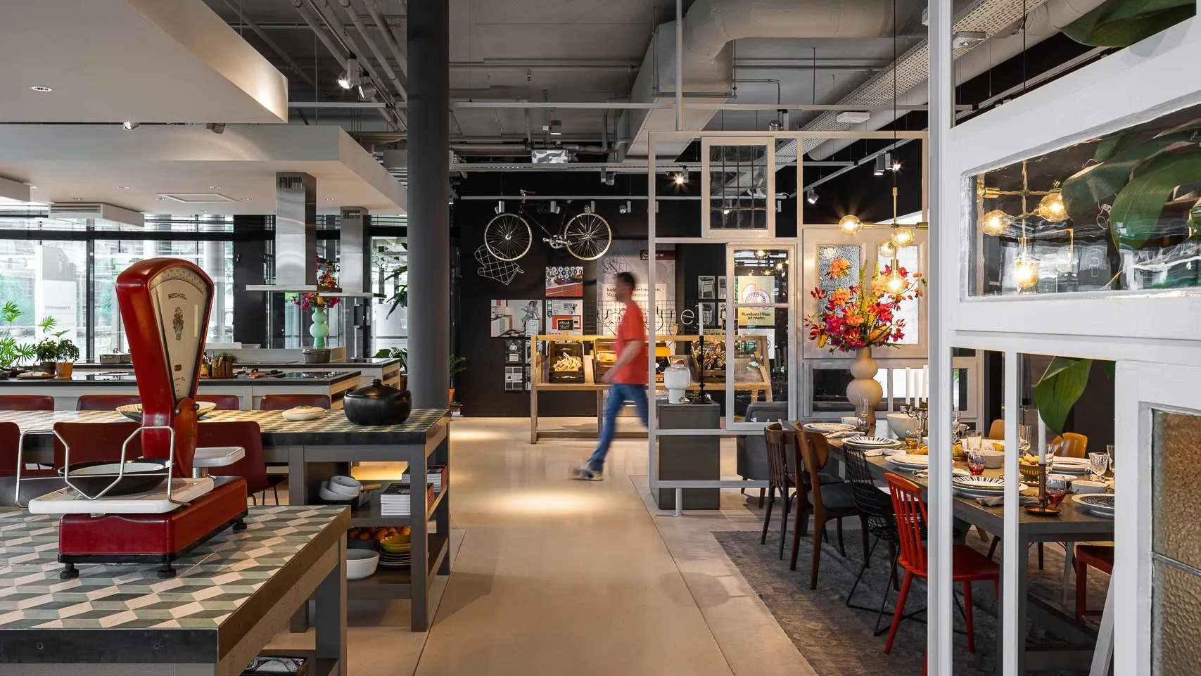 Bruisend café interieur met eclectische inrichting, zitplaatsen en een persoon die door de ruimte loopt.
