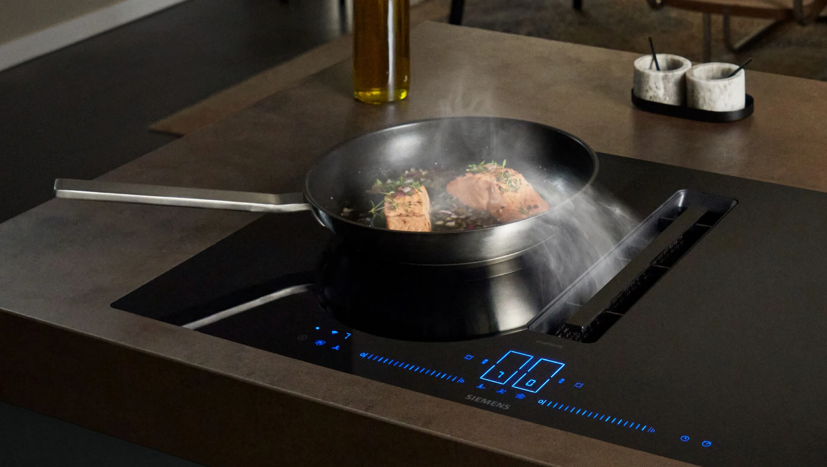 Cooking pan with sizzling food on a modern induction cooktop with digital display.