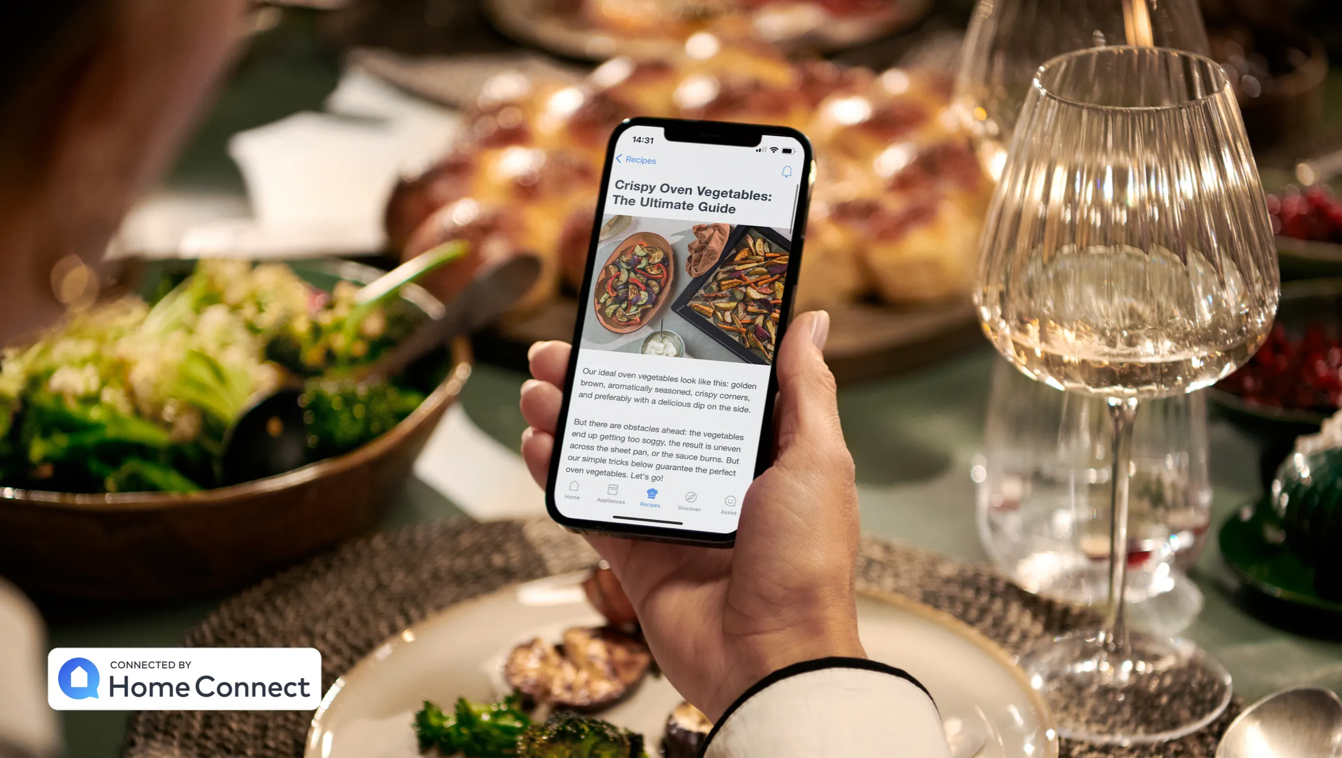 Person holding smartphone displaying food image on table with wine glasses and salad bowl.