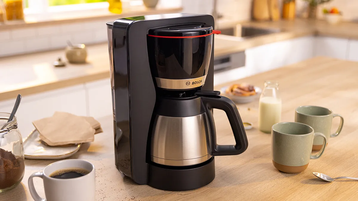 Máy pha cà phê MyMoment trên bếp cạnh những tách cà phê. 
