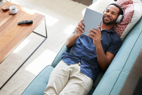 Man relaxing on sofa holding iPad