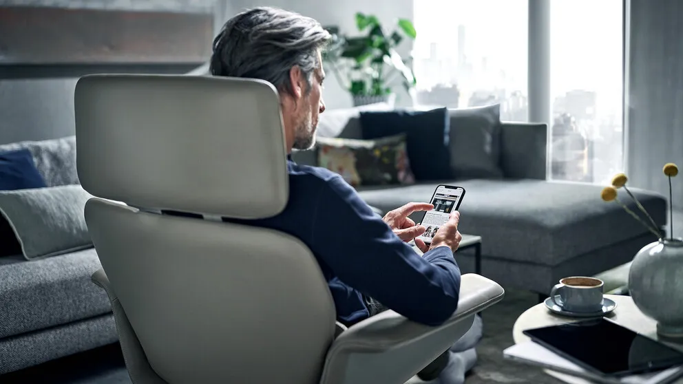 Man sat on a chair in the living room, using his phone