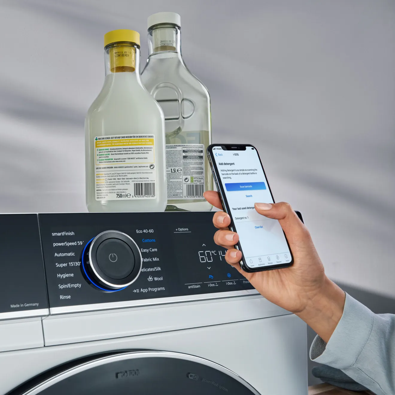 Washing machine with detergent bottles, smartphone app, and temperature display.