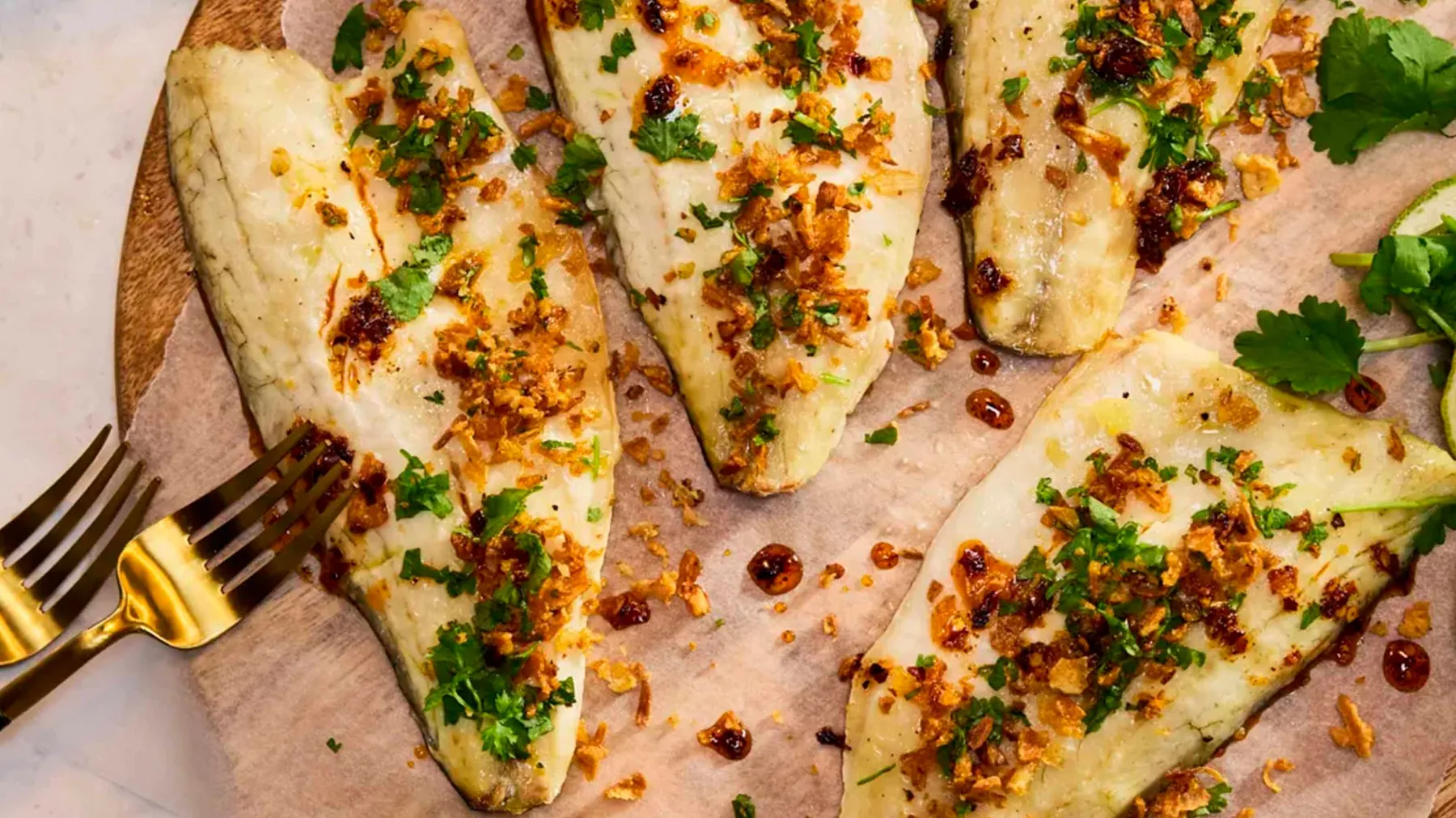 Grilled chicken breasts with herbs, spices, and lemon garnish on a wooden surface.