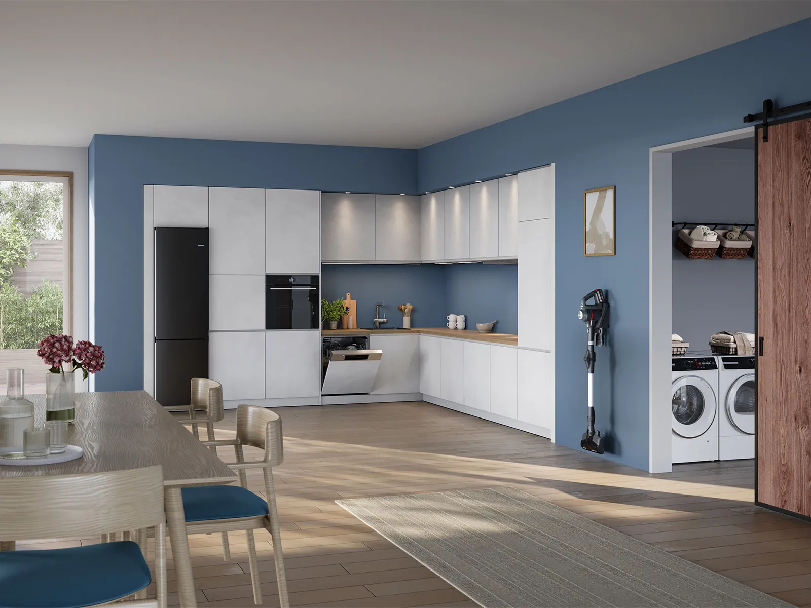 Moderne, helle Küche mit Essbereich, eleganten Schränken, schwarzem Kühlschrank und Eingang zum Hauswirtschaftsraum mit Schiebetür.