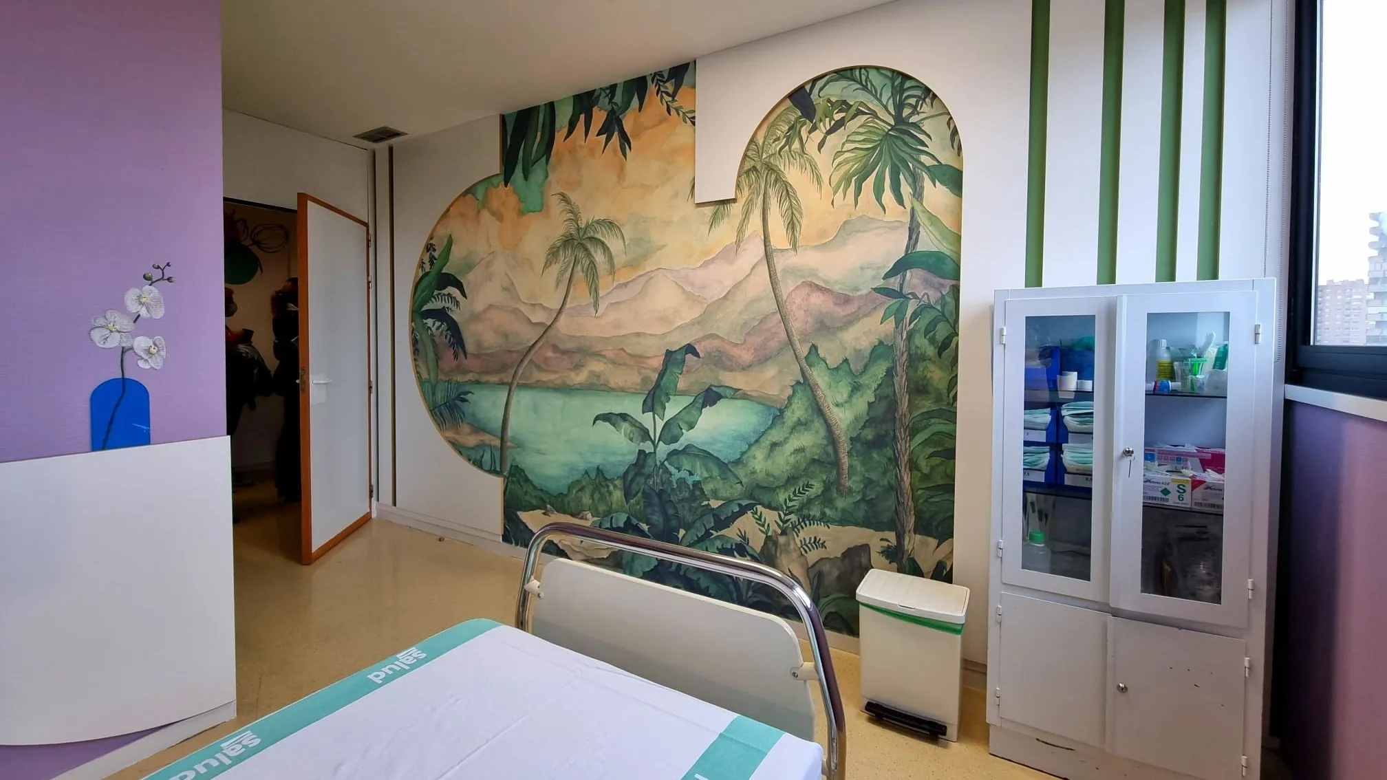 Mural tropical en habitación de hospital, con cama y armario. 