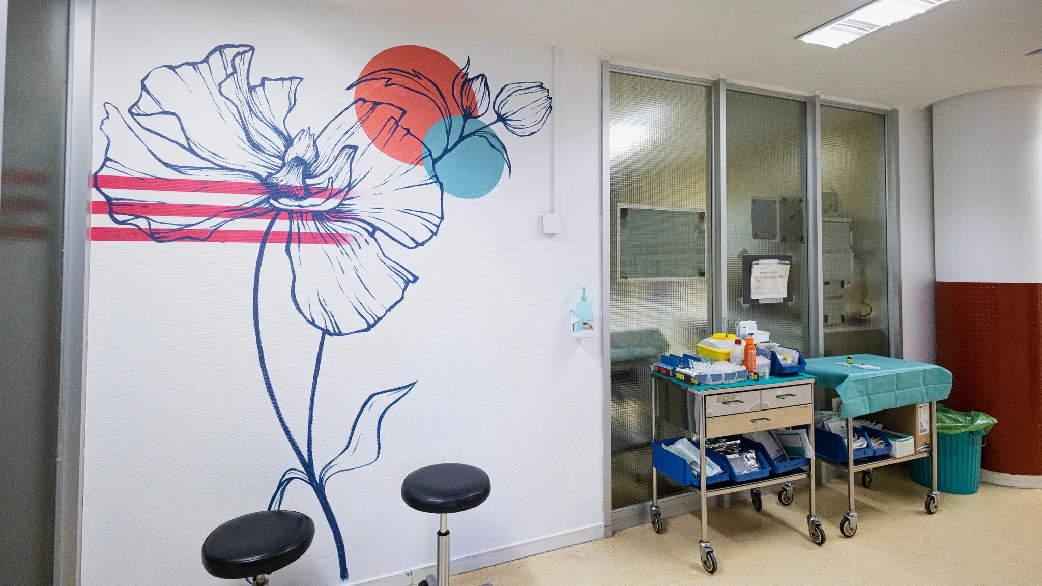 Mural floral colorido en la pared, equipo médico y suministros en la habitación, diseño moderno y vibrante. 