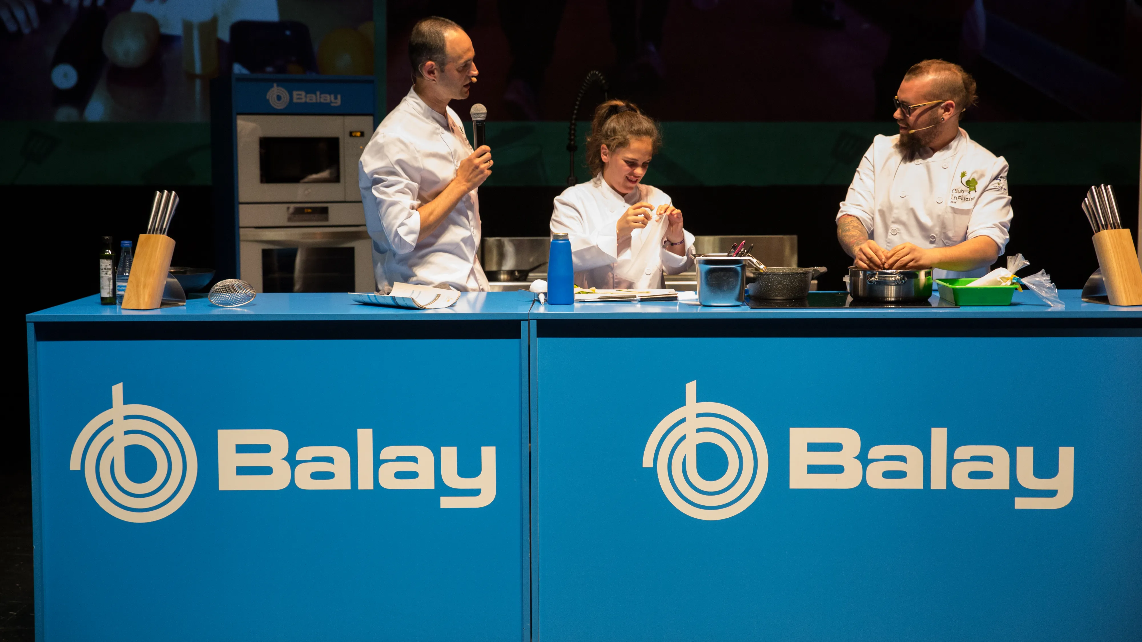 Tres chefs preparando comida en un evento de demostración de cocina de Balay. 