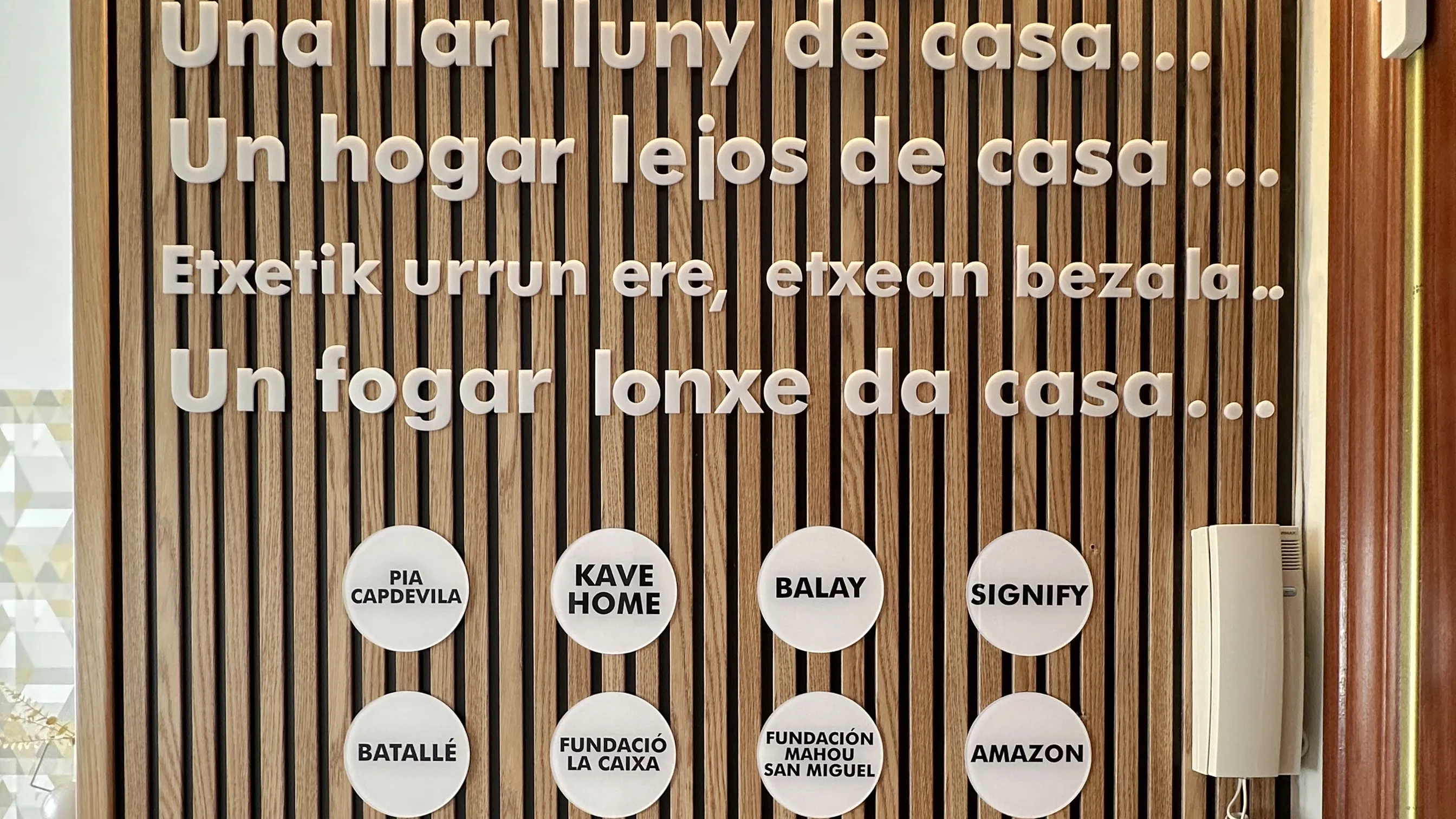 Muro de listones de madera con texto en español mostrando las marcas colaboradoras 
