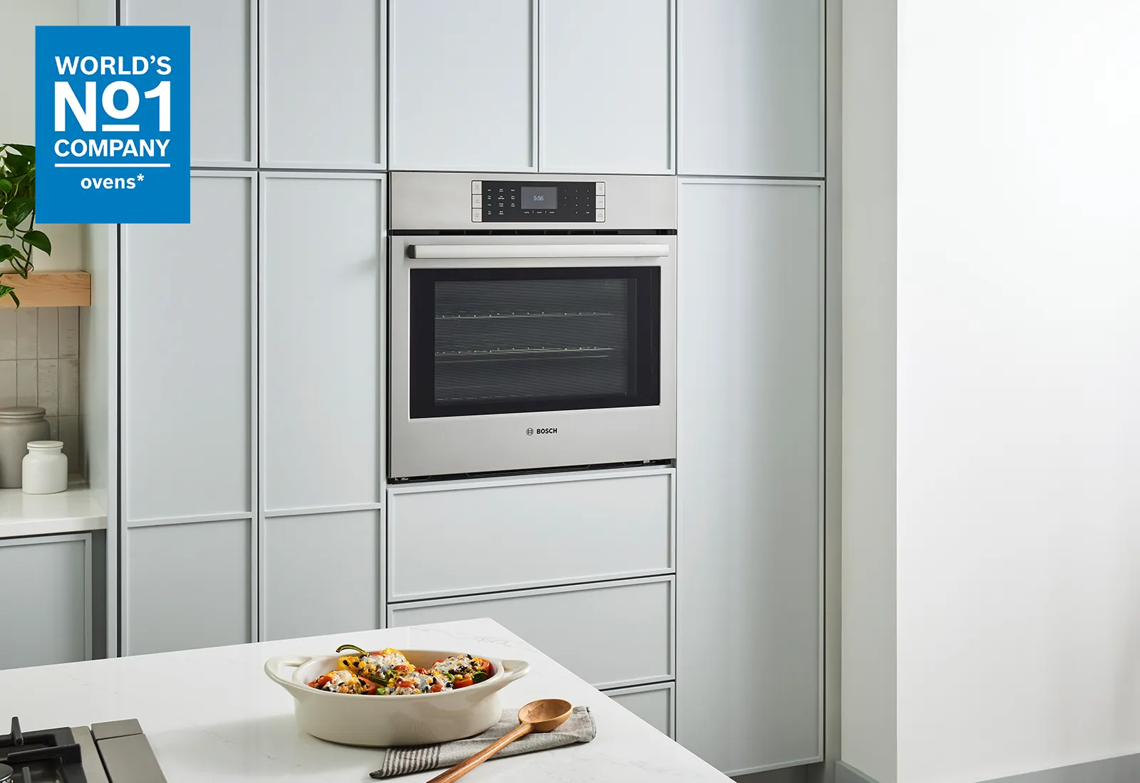 Modern kitchen featuring a Bosch oven built into sleek cabinetry, with a dish of colorful food on the countertop and a tagline for the brand.