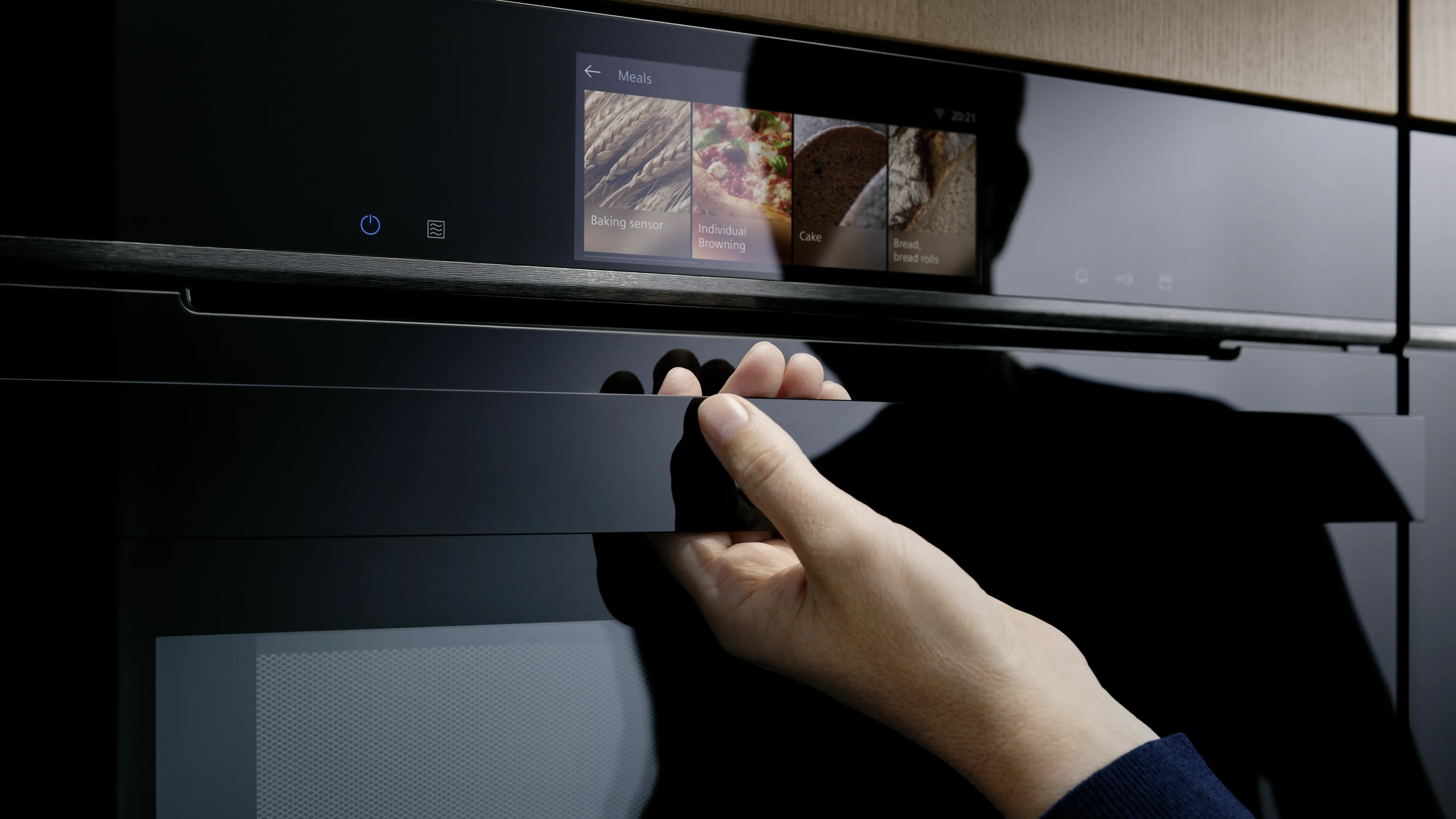 Ruka muže těsně před otevřením trouby Siemens.