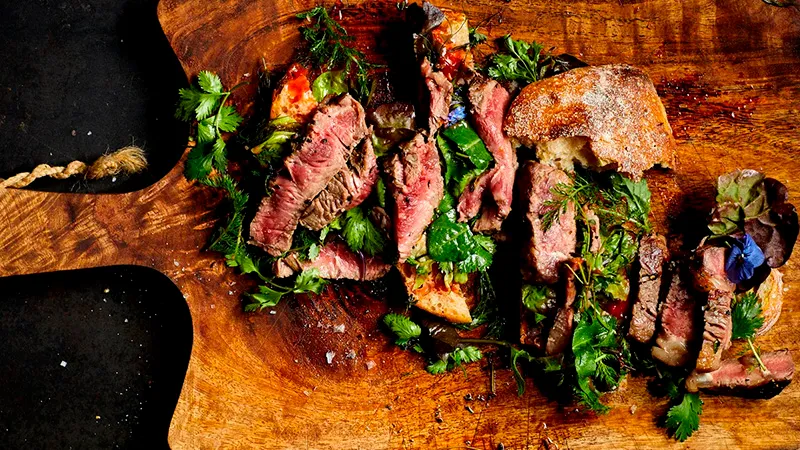 Aufgeschnittenes Steak (in Streifen) auf Holzbrett serviert