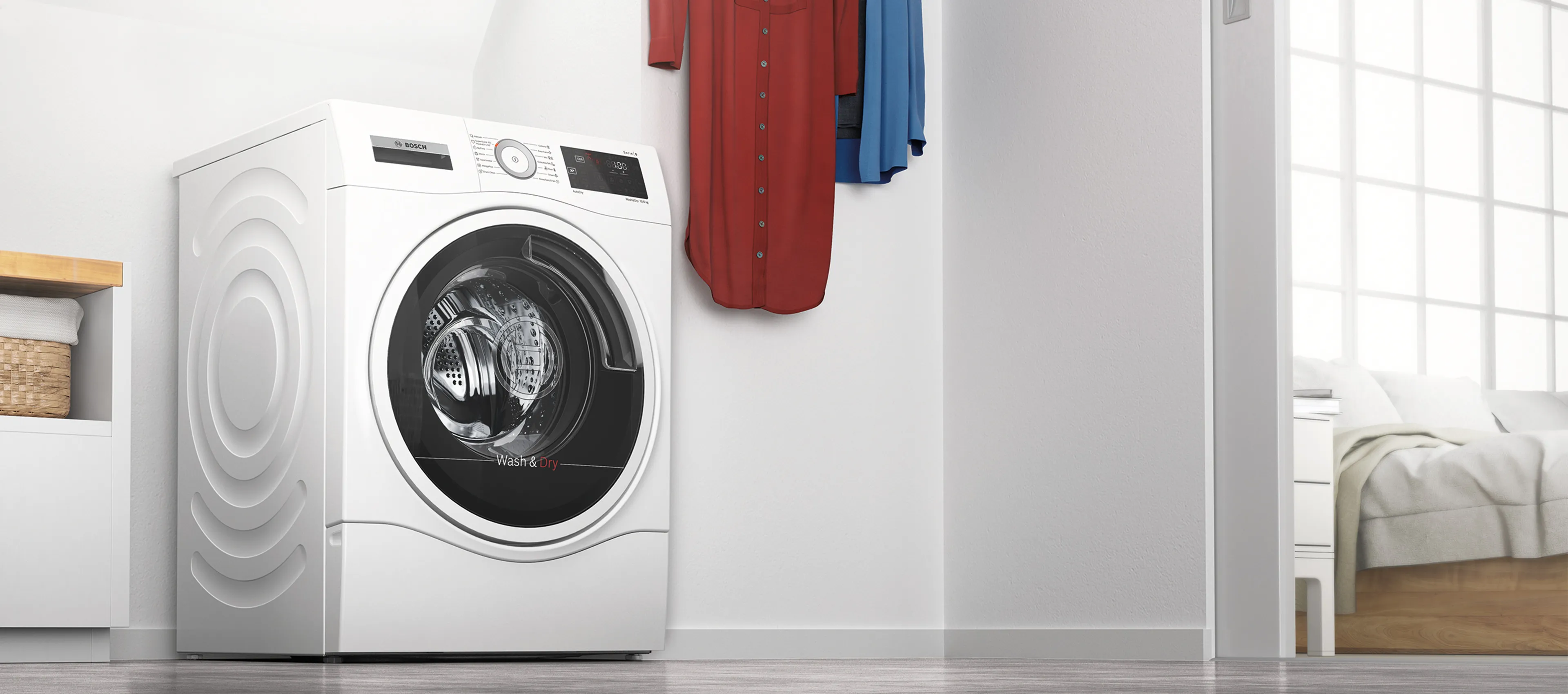 Un lave-linge séchant dans une buanderie lumineuse à côté d'une armoire ouverte contenant des chemises fraîchement lavées.