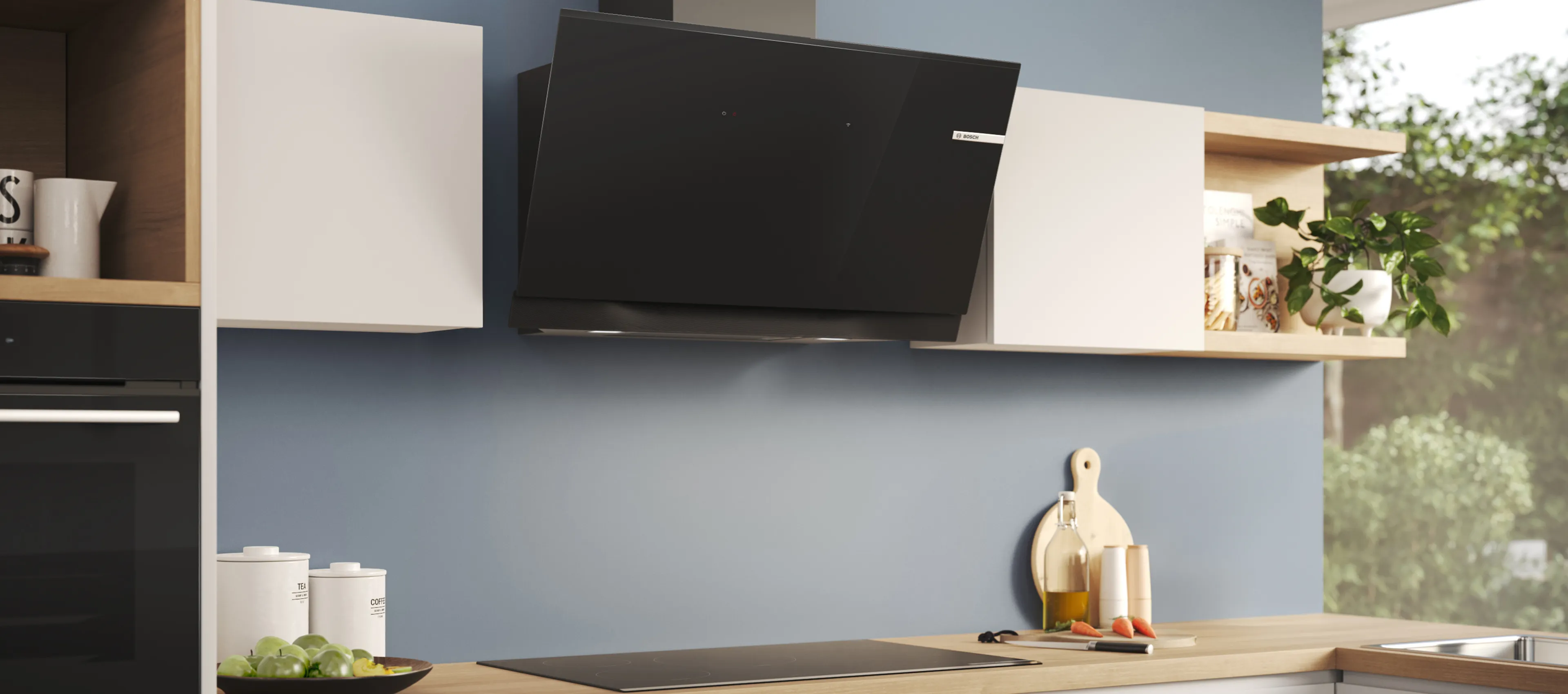 Eine Schräghaube ist an einer blaugrauen Wand über einem Kochfeld in einer modernen Küche montiert.