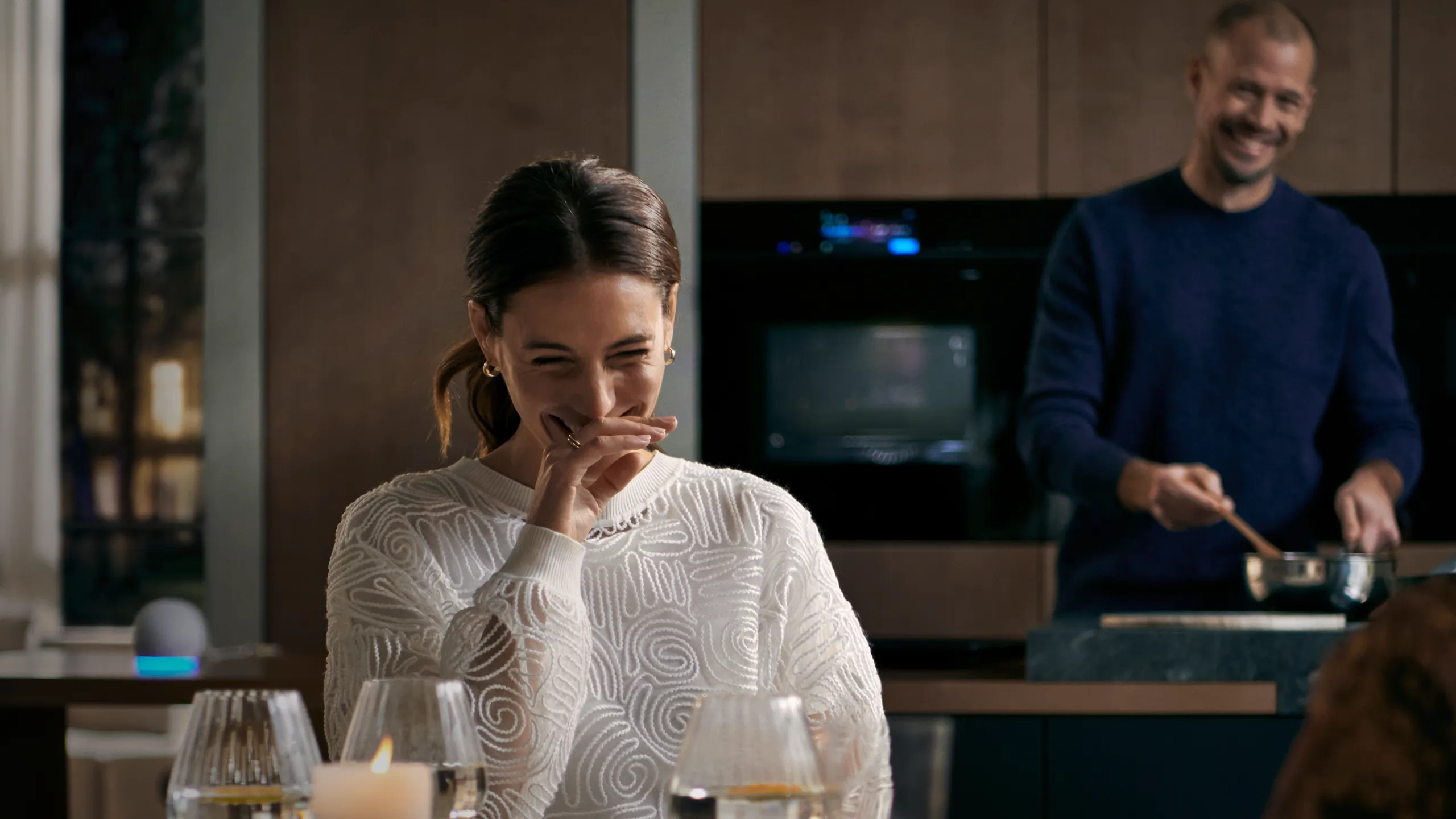 Two people in a Siemens Kitchen with one sat down laughing