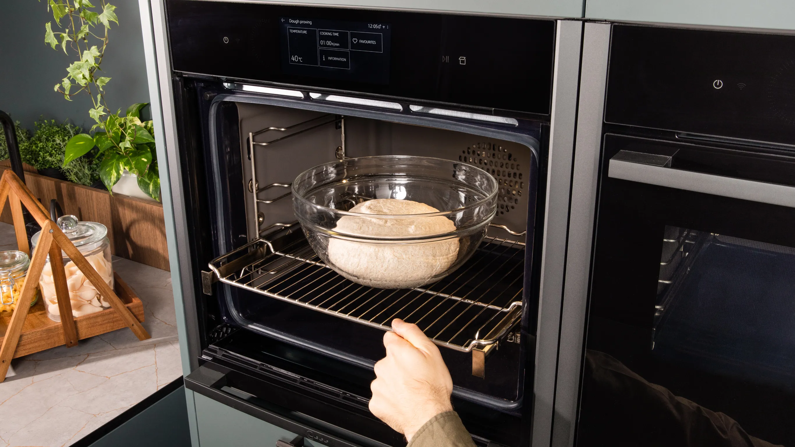 Backofen mit Backteller innen, Hand erreichen, Geschirr, Küchentisch mit Pflanzen und Utensilien zu entfernen.