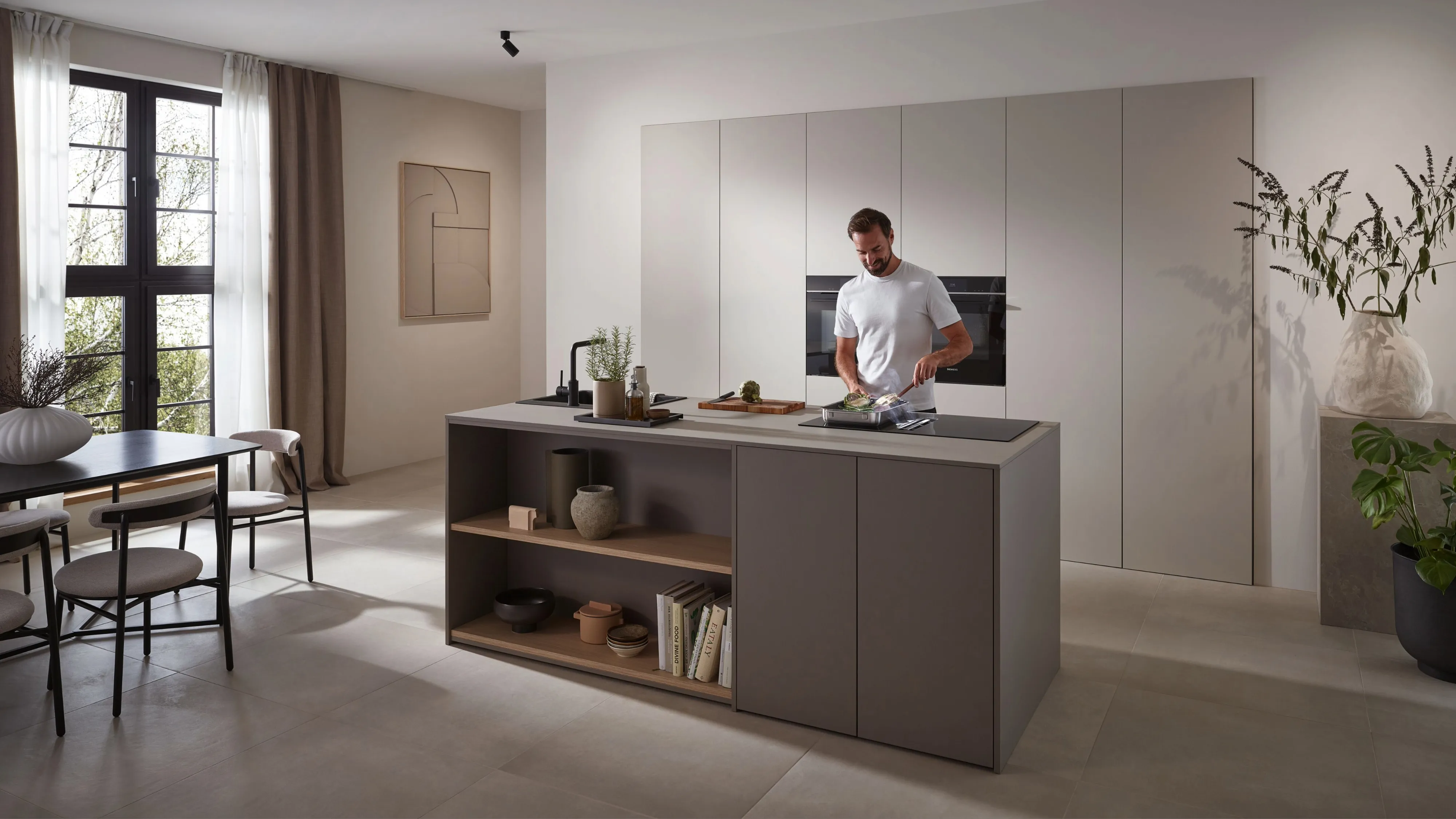 Un hombre cocina en una placa con extractor integrado en una cocina abierta al salón