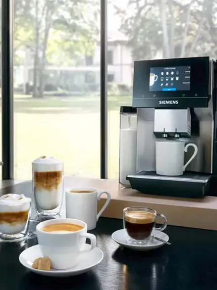 Ekspres Siemens obok filiżanek kawowych, w tym espresso, latte i cappuccino, w jasnym otoczeniu