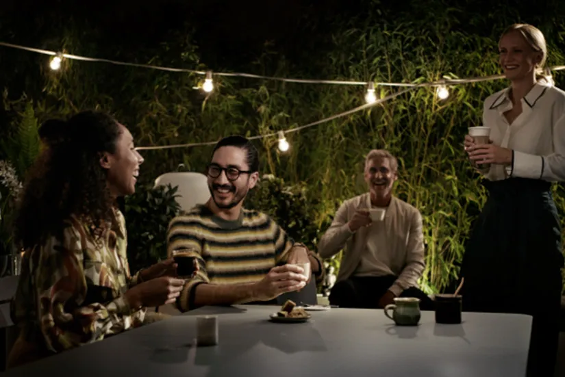 Przytulne spotkanie na świeżym powietrzu – cztery osoby dzielące się napojami i deserami wśród zieleni