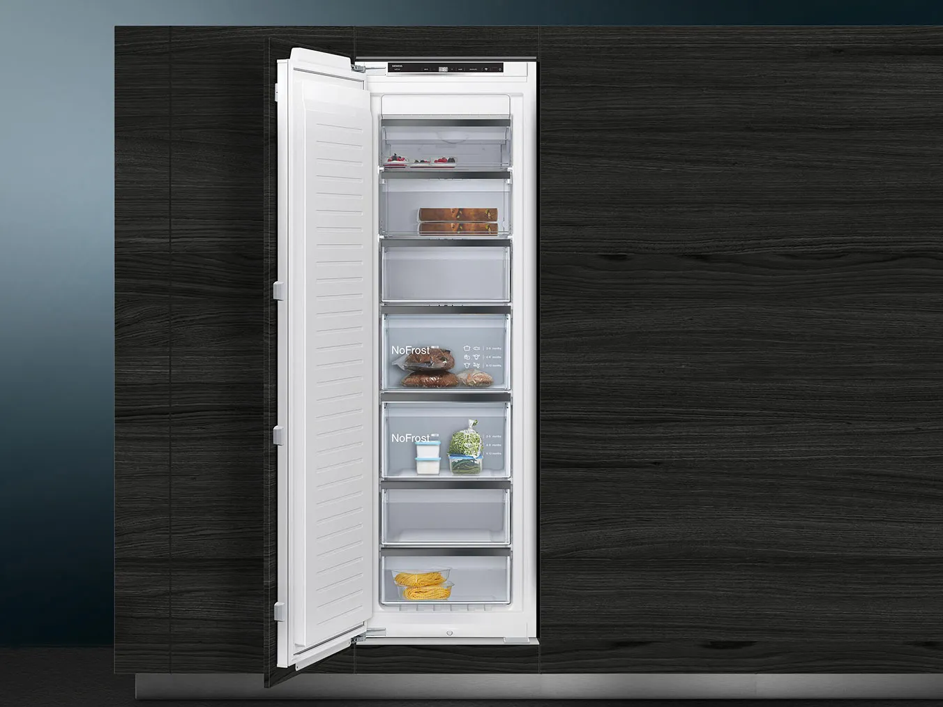 Un congelatore alto e aperto, inserito in un mobile in legno scuro, che contiene sugli scaffali alcuni prodotti alimentari, tra cui carne confezionata, pane e bevande.