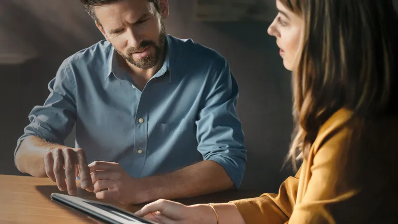 A man and a woman looking at an electronic tablet