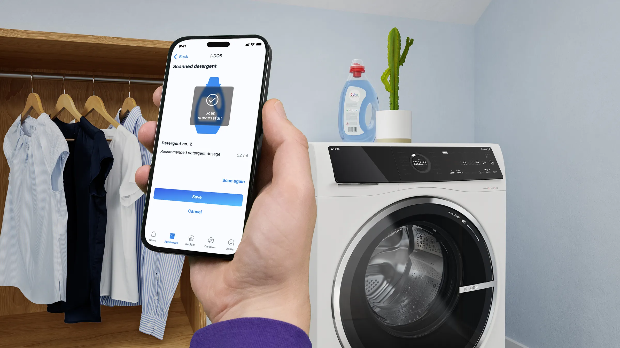 Eine Hand hält ein Smartphone im Vordergrund, auf dem eine erfolgreiche Waschmittel-Scan-Meldung der i-DOS Funktion angezeigt wird. Im Hintergrund steht eine weiße Bosch-Waschmaschine.