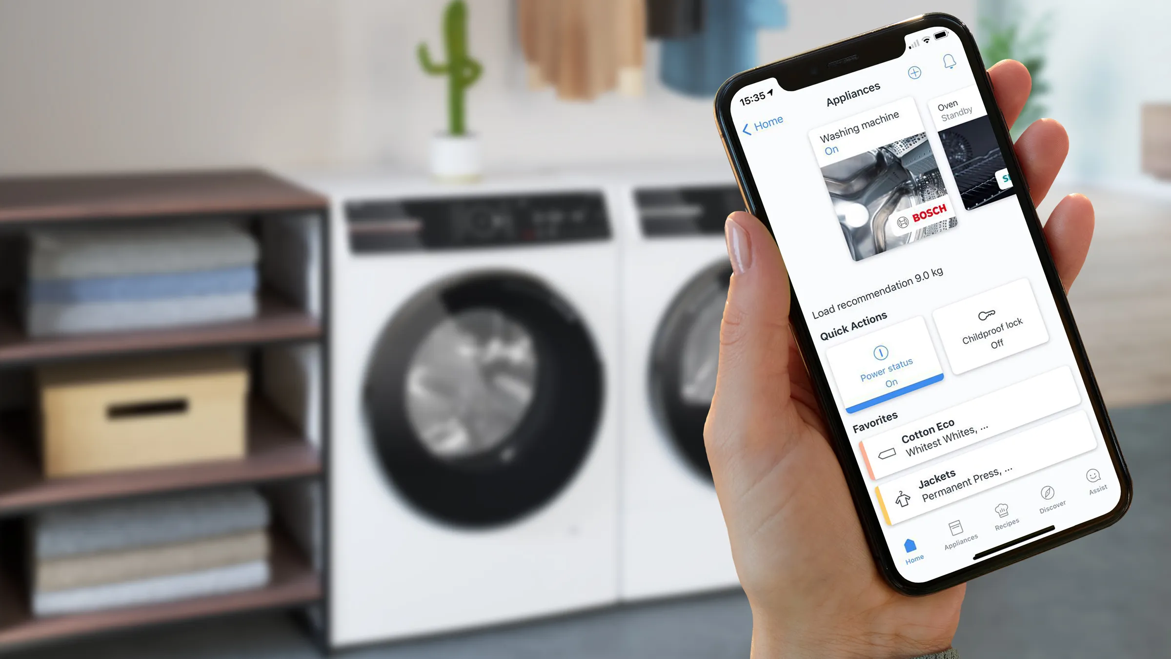 Smartphone mit einer Haushaltsgerät-App, mit einer Waschmaschine im Hintergrund sichtbar.