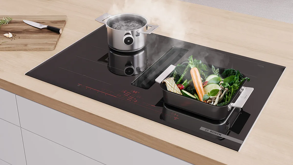 Induktion Kochfeld mit Dampfkessel und Behälter aus frischem Gemüse auf Holz Küchentheke.
