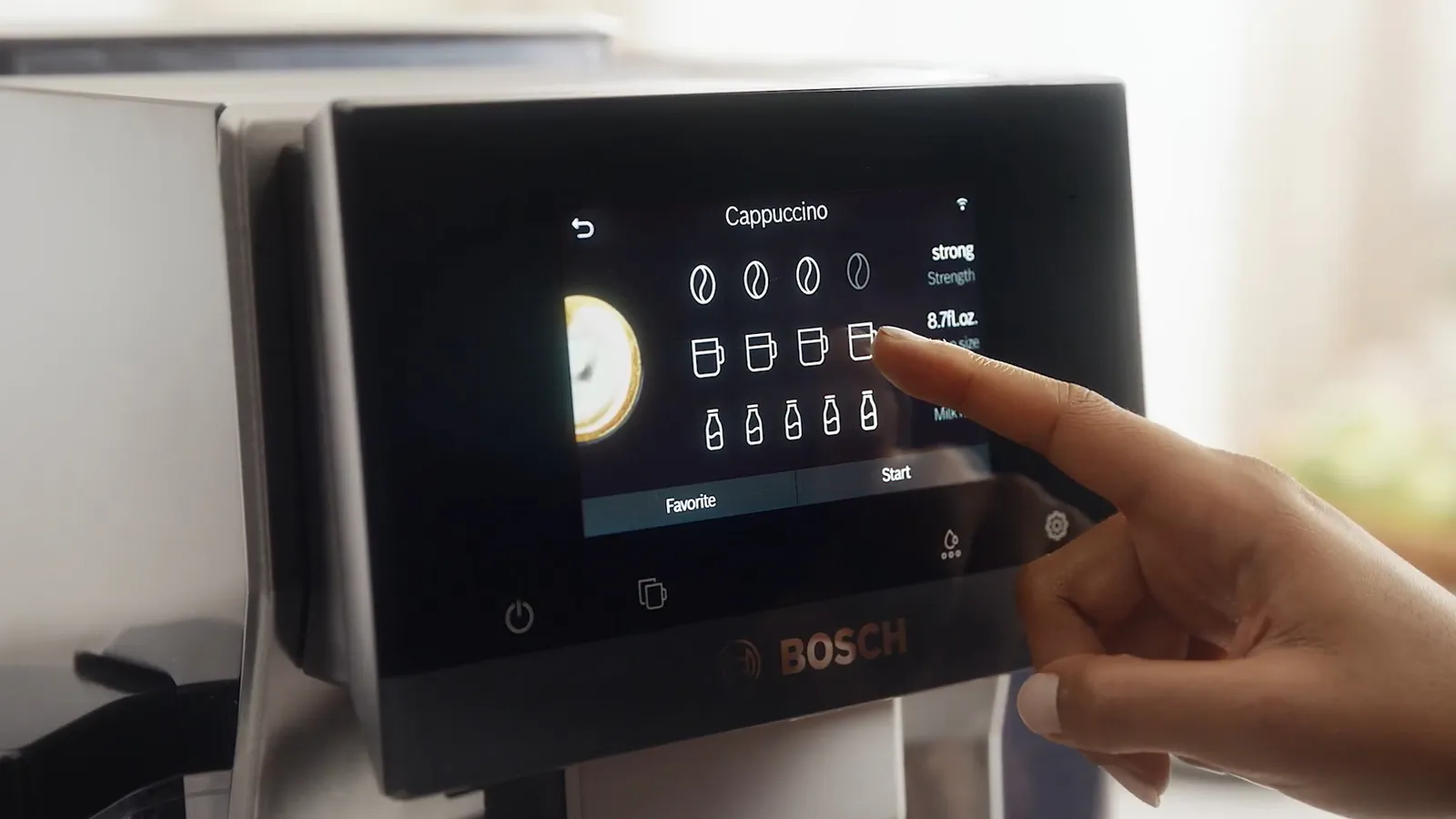 Close-up of a Bosch coffee machine touchscreen displaying cappuccino options.